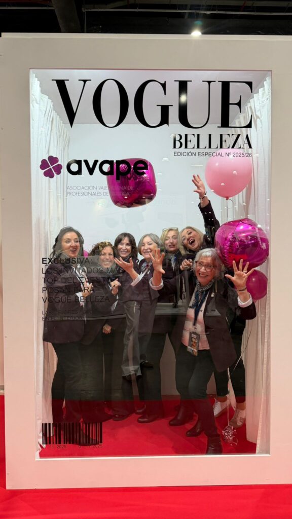 Grupo de socias de AVAPE con la americana ciruela de la asociación, levantando las manos y sujetando globos, dentro del photocall de Vogue Belleza